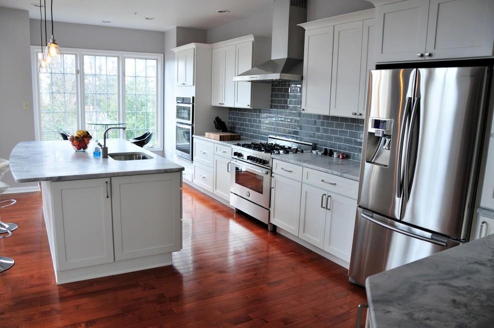 Transitional l-shaped open concept kitchen photo in Philadelphia with an undermount sink, shaker cabinets, white cabinets, quartzite countertops, gray backsplash, glass tile backsplash and stainless steel appliances