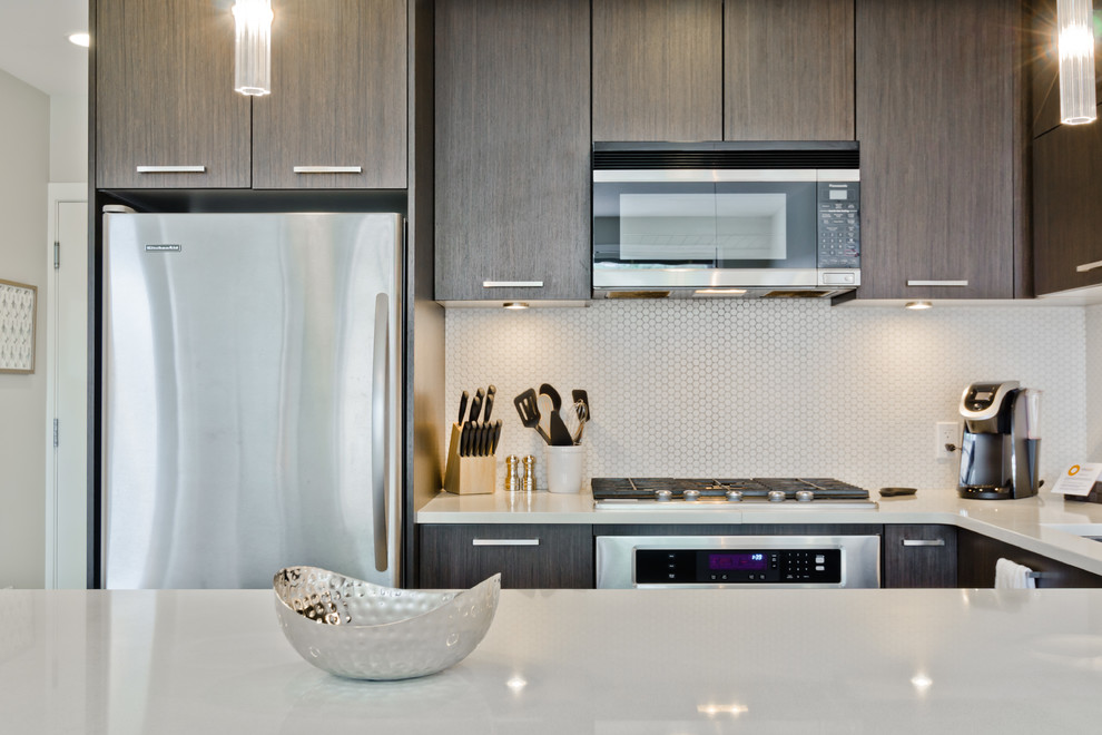 This is an example of a medium sized classic u-shaped kitchen in Calgary with a submerged sink, flat-panel cabinets, granite worktops, white splashback, stainless steel appliances and medium hardwood flooring.