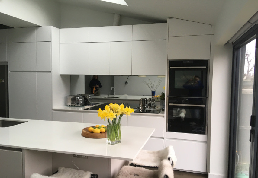 Immagine di un cucina con isola centrale minimalista con ante lisce, ante grigie e paraspruzzi a specchio