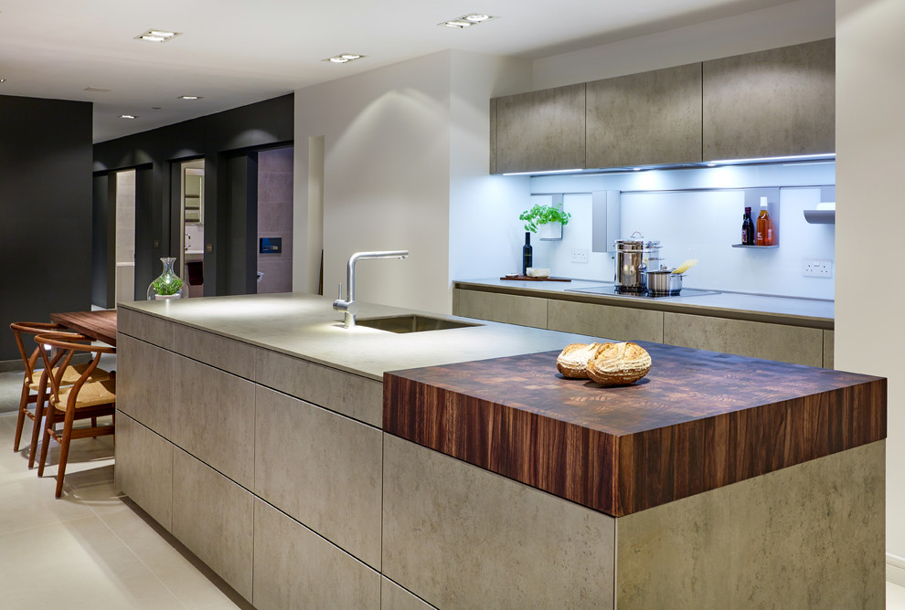 Inspiration for a large contemporary single-wall kitchen/diner in Wiltshire with an integrated sink, flat-panel cabinets, grey cabinets, concrete worktops, white splashback, glass sheet splashback, black appliances and an island.