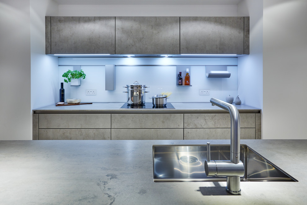 Foto på ett stort funkis linjärt kök och matrum, med en integrerad diskho, släta luckor, grå skåp, bänkskiva i betong, vitt stänkskydd, glaspanel som stänkskydd och en köksö