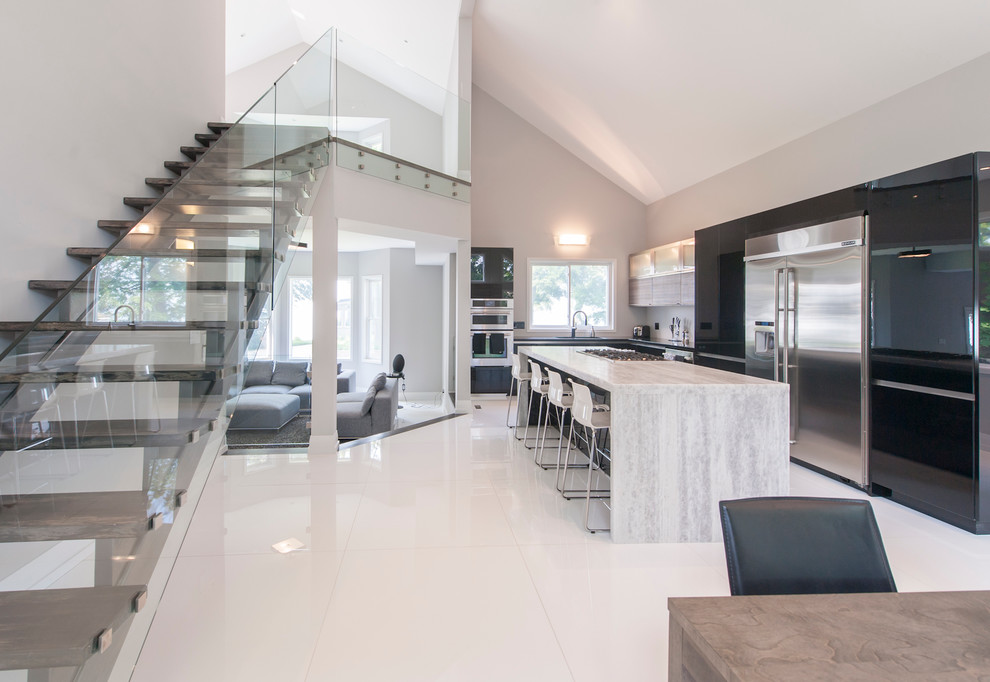 Expansive contemporary l-shaped open plan kitchen in Toronto with an island, flat-panel cabinets, granite worktops, stainless steel appliances and ceramic flooring.