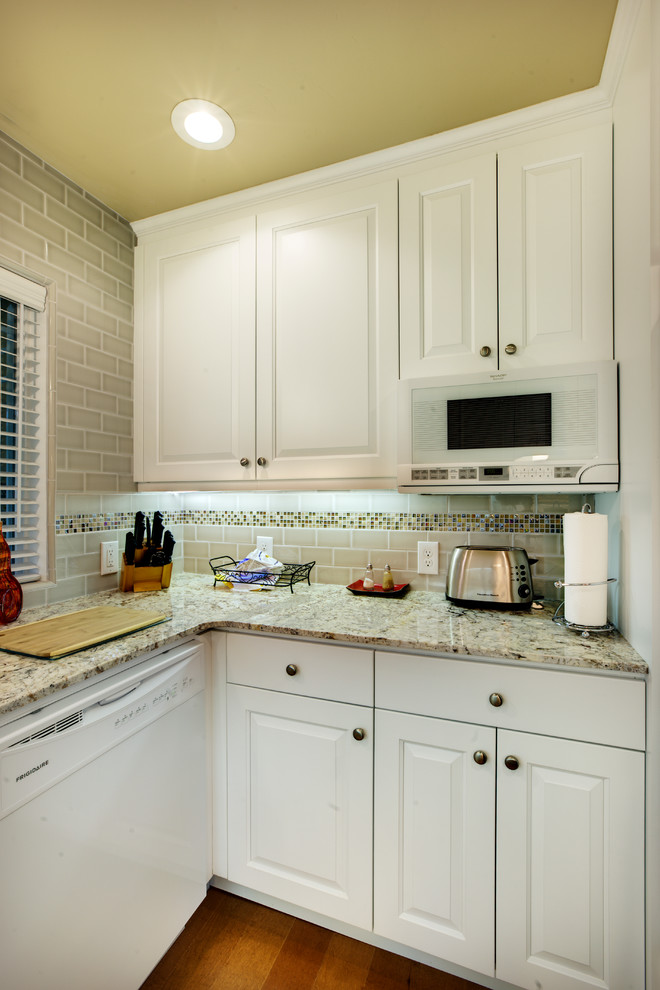 This is an example of a small classic u-shaped enclosed kitchen in Sacramento with a double-bowl sink, white cabinets, granite worktops, multi-coloured splashback, white appliances, medium hardwood flooring, no island, raised-panel cabinets and glass tiled splashback.