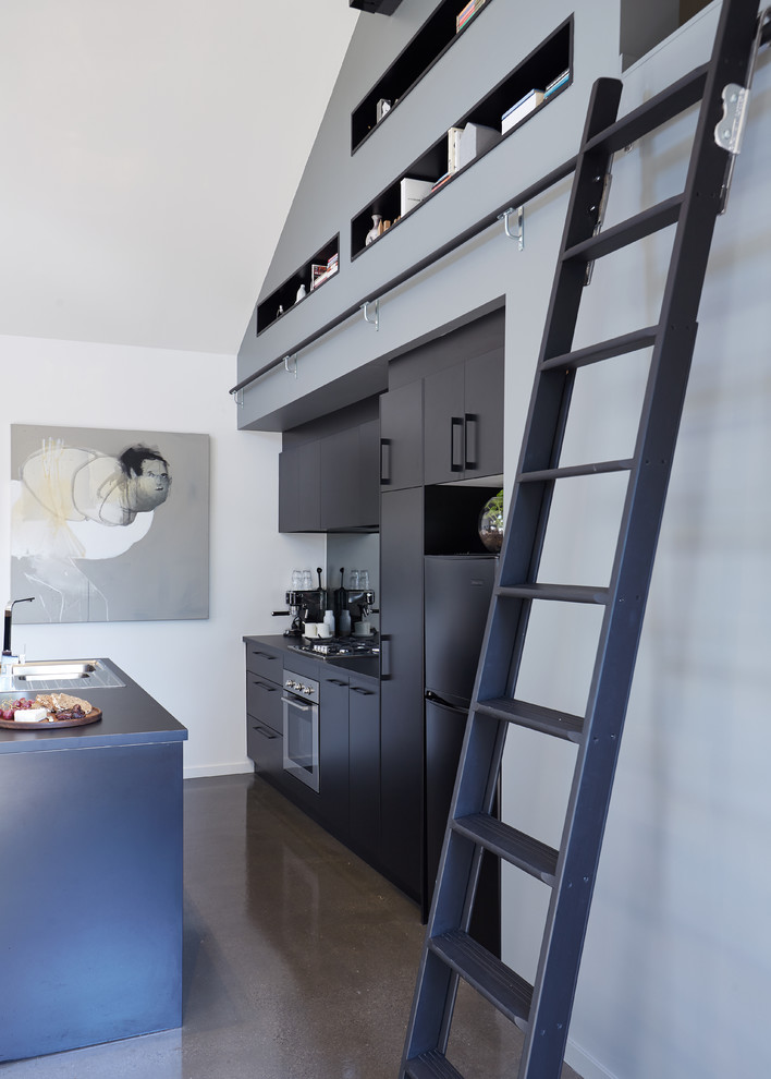 Immagine di una cucina design di medie dimensioni con lavello da incasso, ante nere e elettrodomestici in acciaio inossidabile