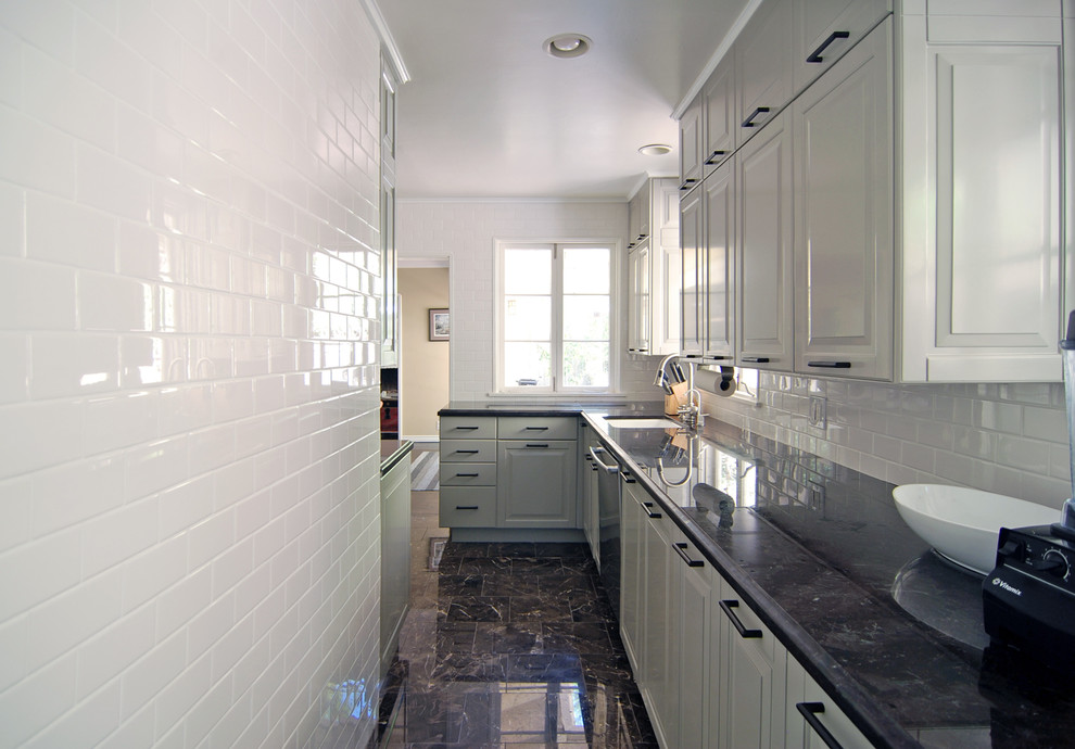Geschlossene Küche in L-Form mit Unterbauwaschbecken, profilierten Schrankfronten, grauen Schränken, Granit-Arbeitsplatte, Küchenrückwand in Weiß, Rückwand aus Metrofliesen und Küchengeräten aus Edelstahl in Los Angeles