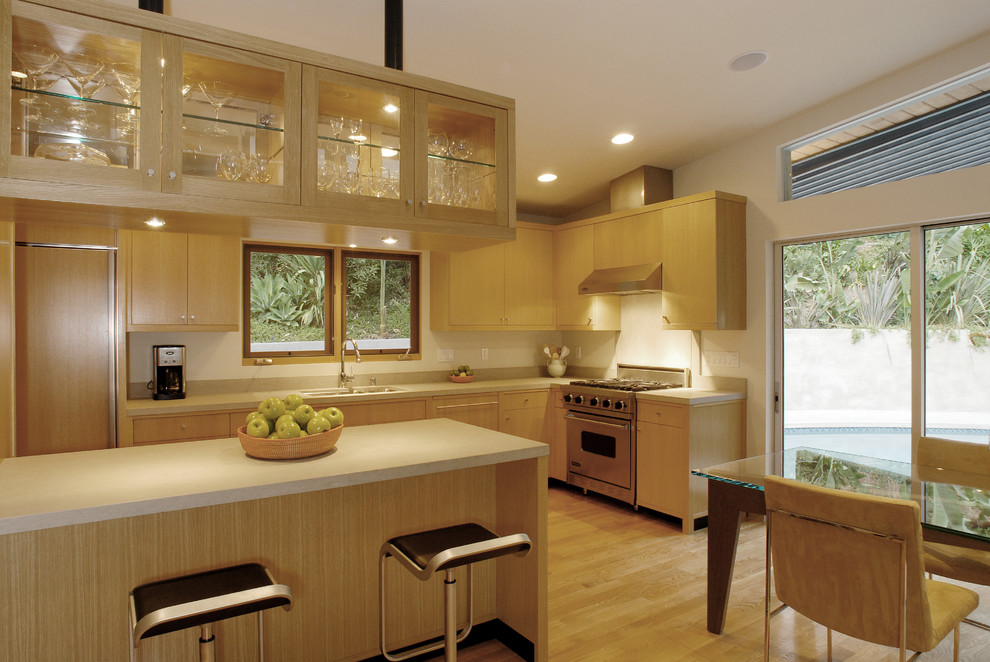 Modern inredning av ett mellanstort kök, med en undermonterad diskho, släta luckor, skåp i ljust trä, bänkskiva i kalksten, grått stänkskydd, stänkskydd i sten, integrerade vitvaror, ljust trägolv och en halv köksö