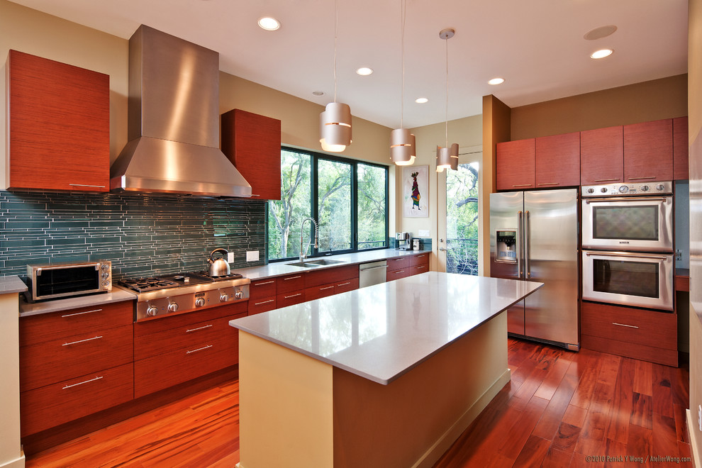 Immagine di una cucina minimal con elettrodomestici in acciaio inossidabile, lavello a doppia vasca, ante lisce, ante in legno bruno e paraspruzzi blu