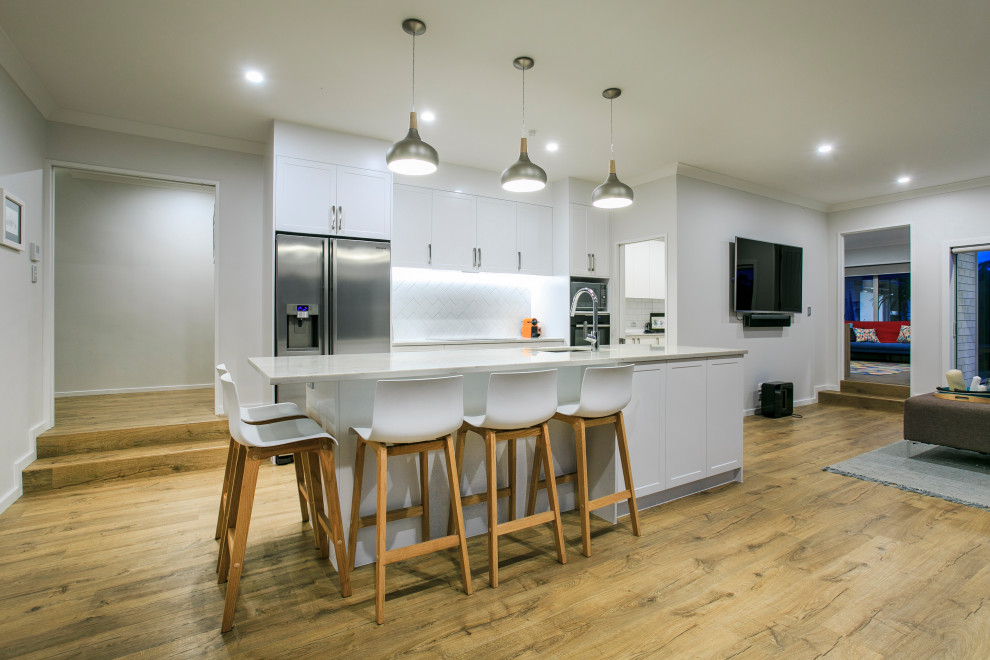 Esempio di una cucina moderna di medie dimensioni con lavello sottopiano, paraspruzzi bianco, paraspruzzi con piastrelle in ceramica, elettrodomestici in acciaio inossidabile e top bianco