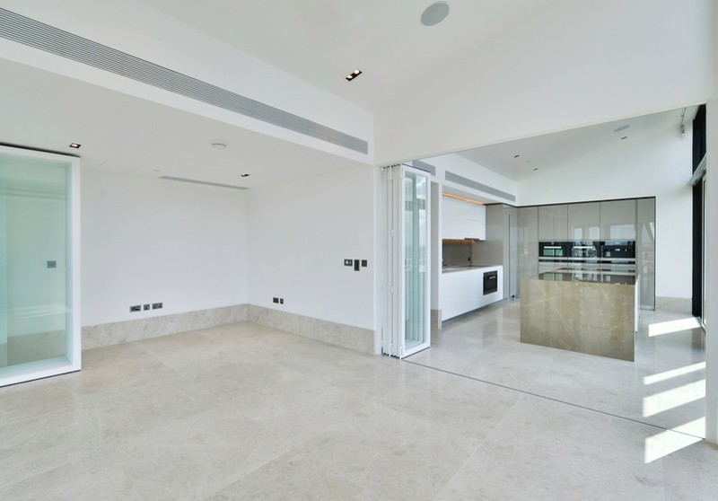 Large contemporary l-shaped open plan kitchen in London with flat-panel cabinets, grey cabinets, marble worktops, black appliances and an island.