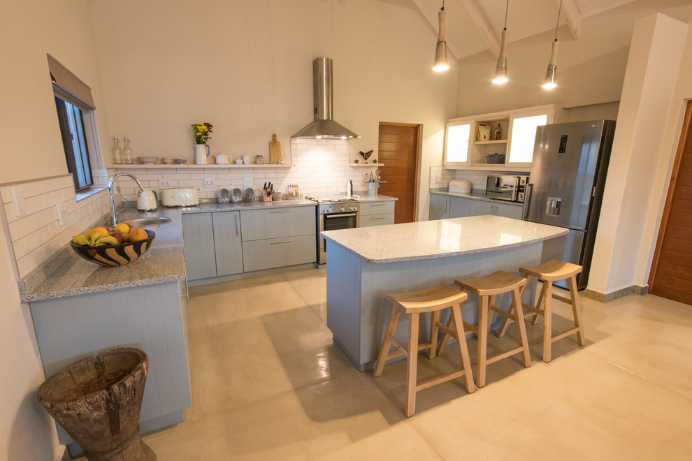 Medium sized farmhouse u-shaped kitchen/diner in Other with a submerged sink, flat-panel cabinets, turquoise cabinets, granite worktops, white splashback, metro tiled splashback, stainless steel appliances, concrete flooring, an island, beige floors and grey worktops.