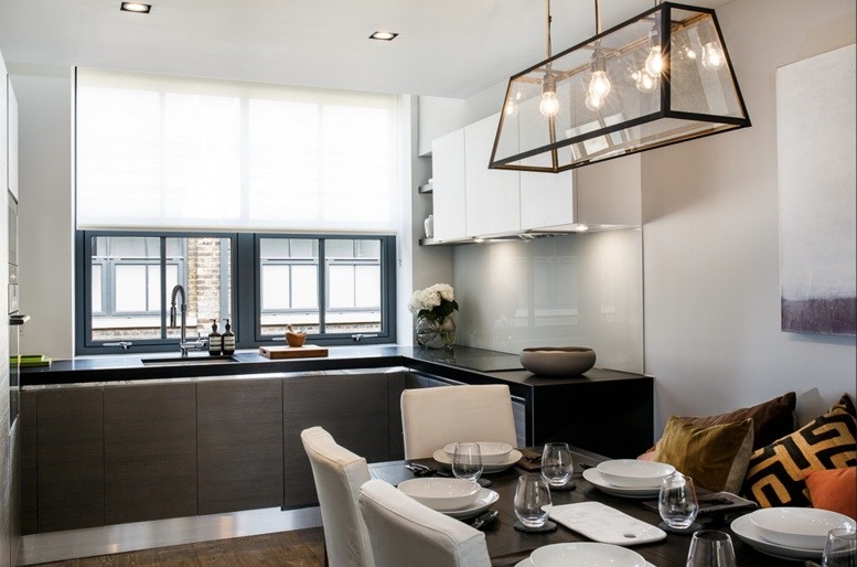 Photo of a small urban l-shaped kitchen/diner in London with a submerged sink, flat-panel cabinets, brown cabinets, composite countertops, white splashback, glass sheet splashback, stainless steel appliances, medium hardwood flooring, no island, brown floors and black worktops.