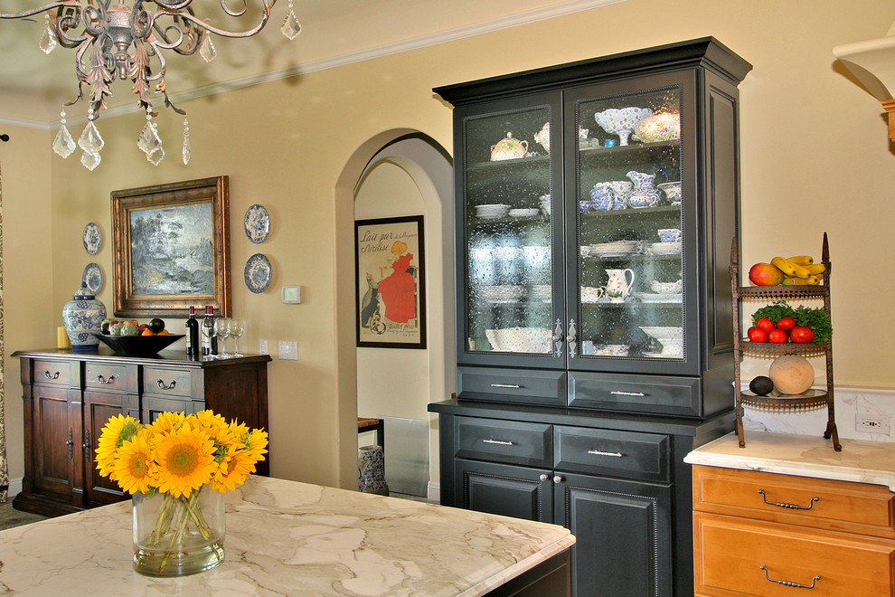 Example of a classic kitchen design in San Diego with glass-front cabinets, marble countertops and black cabinets