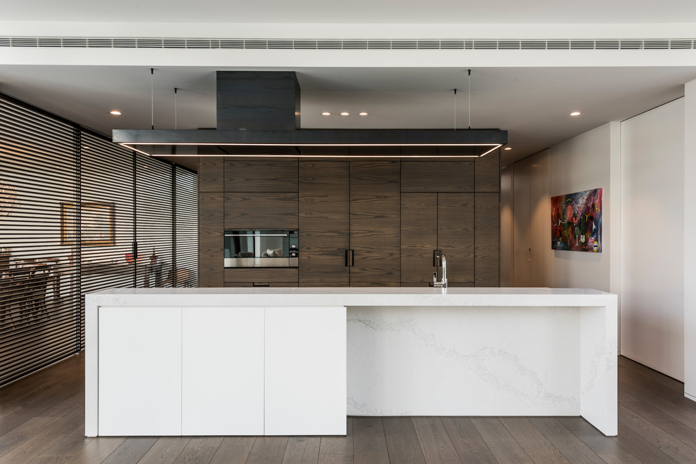 Zweizeilige Moderne Küche mit Vorratsschrank, Marmor-Arbeitsplatte, schwarzen Elektrogeräten, Kücheninsel und hellbraunen Holzschränken in Christchurch