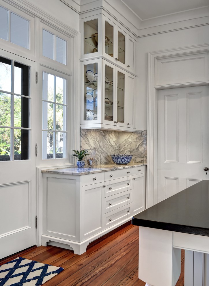 Inspiration for a large transitional u-shaped medium tone wood floor kitchen remodel in Charleston with an undermount sink, beaded inset cabinets, white cabinets, marble countertops, gray backsplash, stone slab backsplash, paneled appliances and an island