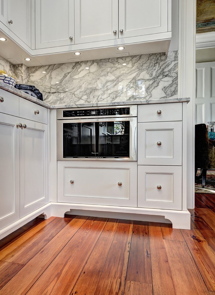 Example of a large transitional u-shaped medium tone wood floor kitchen design in Charleston with an undermount sink, beaded inset cabinets, white cabinets, marble countertops, gray backsplash, stone slab backsplash, paneled appliances and an island