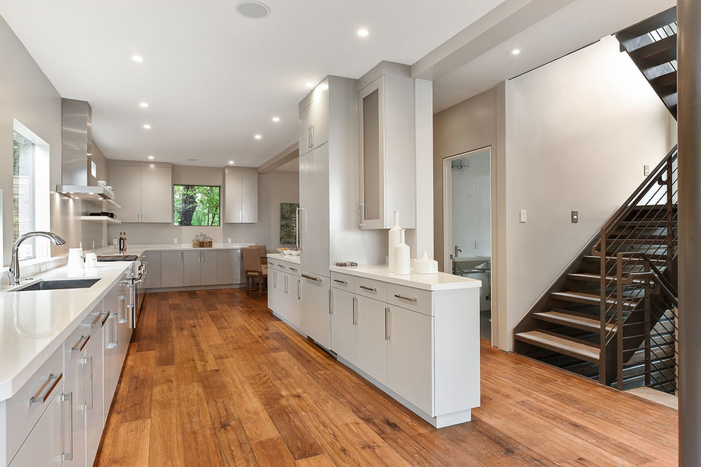 Foto de cocina contemporánea con fregadero bajoencimera, armarios con paneles lisos, puertas de armario blancas y suelo de madera en tonos medios