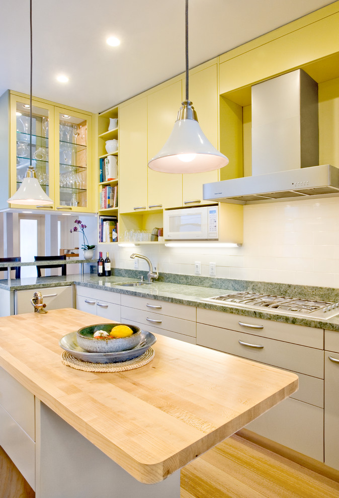 Mittelgroße Moderne Küche mit Unterbauwaschbecken, flächenbündigen Schrankfronten, gelben Schränken, Granit-Arbeitsplatte, Küchenrückwand in Weiß, Küchengeräten aus Edelstahl, hellem Holzboden, Kücheninsel und grüner Arbeitsplatte in San Francisco