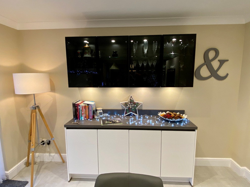 Inspiration for a large contemporary l-shaped open plan kitchen in Sussex with a built-in sink, flat-panel cabinets, white cabinets, laminate countertops, grey splashback, black appliances, vinyl flooring, multiple islands, beige floors and grey worktops.