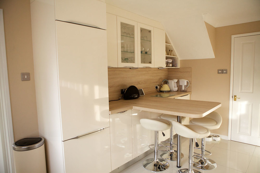 Bild på ett avskilt, mellanstort funkis kök, med släta luckor, vita skåp, rött stänkskydd, glaspanel som stänkskydd, rostfria vitvaror och en halv köksö