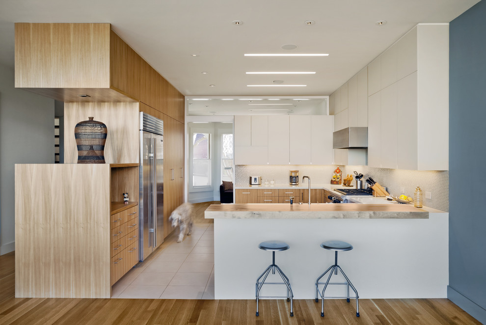 Diseño de cocinas en U minimalista cerrado con armarios con paneles lisos, puertas de armario blancas y electrodomésticos de acero inoxidable