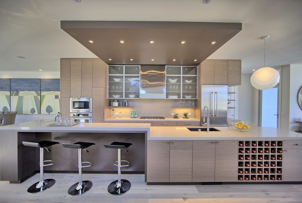 На фото: параллельная кухня в современном стиле с врезной мойкой, плоскими фасадами, светлыми деревянными фасадами, белым фартуком и техникой из нержавеющей стали