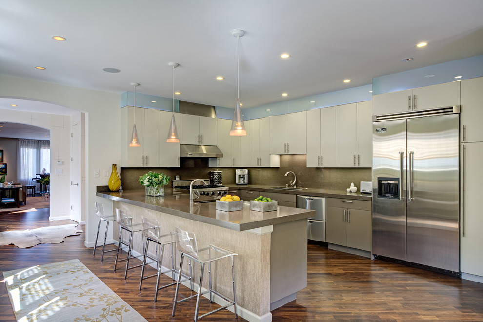 Eat-in kitchen - large contemporary u-shaped medium tone wood floor eat-in kitchen idea in San Francisco with a drop-in sink, flat-panel cabinets, beige cabinets, concrete countertops, beige backsplash, glass tile backsplash and stainless steel appliances