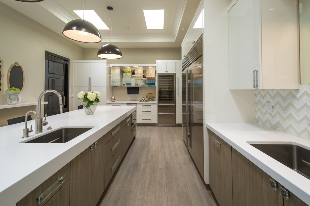 Contemporary l-shaped kitchen in Other with a submerged sink, flat-panel cabinets, white cabinets, multi-coloured splashback, stainless steel appliances, medium hardwood flooring and an island.