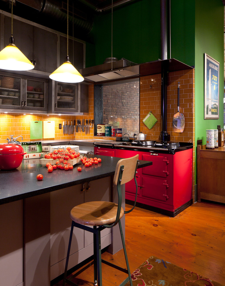ニューヨークにあるインダストリアルスタイルのおしゃれなキッチン (ガラス扉のキャビネット、グレーのキャビネット、オレンジのキッチンパネル、サブウェイタイルのキッチンパネル、カラー調理設備) の写真