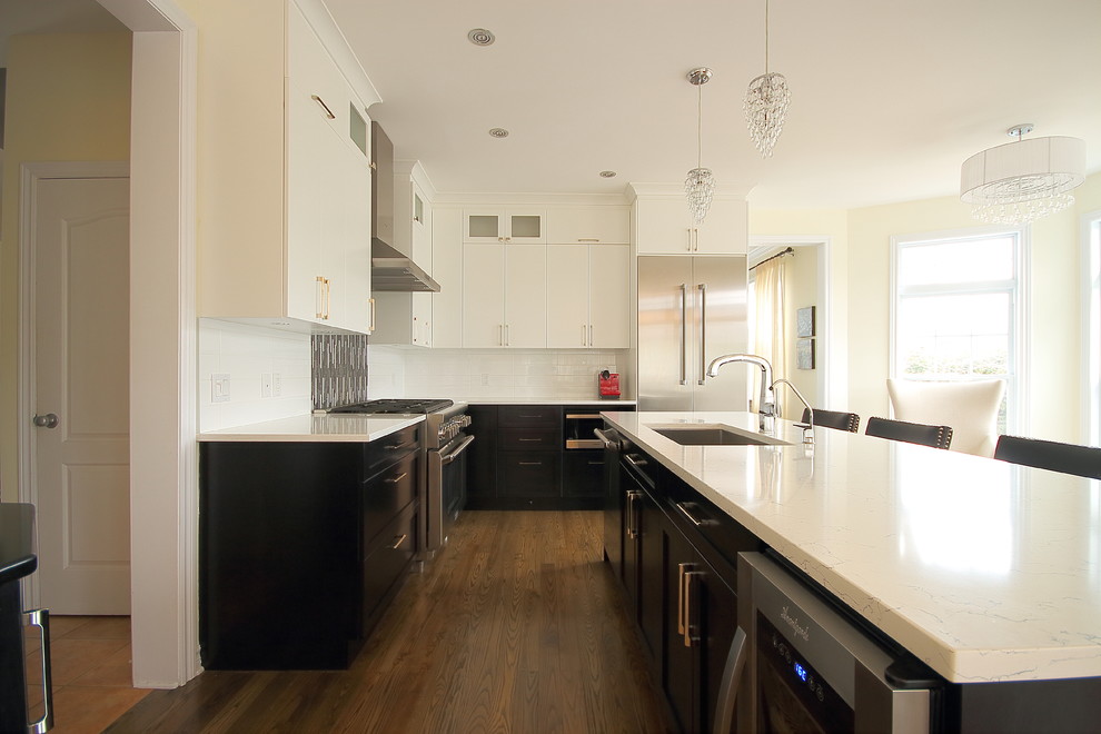 Bild på ett mellanstort funkis kök, med en enkel diskho, luckor med infälld panel, svarta skåp, bänkskiva i kvarts, flerfärgad stänkskydd, rostfria vitvaror, mellanmörkt trägolv och en köksö