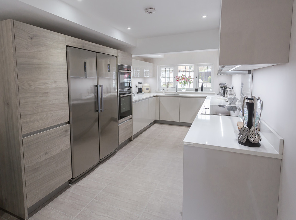 Mittelgroße Moderne Wohnküche in U-Form mit flächenbündigen Schrankfronten, hellen Holzschränken, Quarzit-Arbeitsplatte, Küchengeräten aus Edelstahl und weißer Arbeitsplatte in Hertfordshire