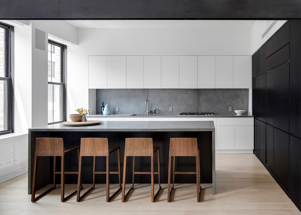 Design ideas for a large contemporary kitchen in New York with a submerged sink, flat-panel cabinets, white cabinets, concrete worktops, grey splashback, cement tile splashback, light hardwood flooring, an island, beige floors and grey worktops.