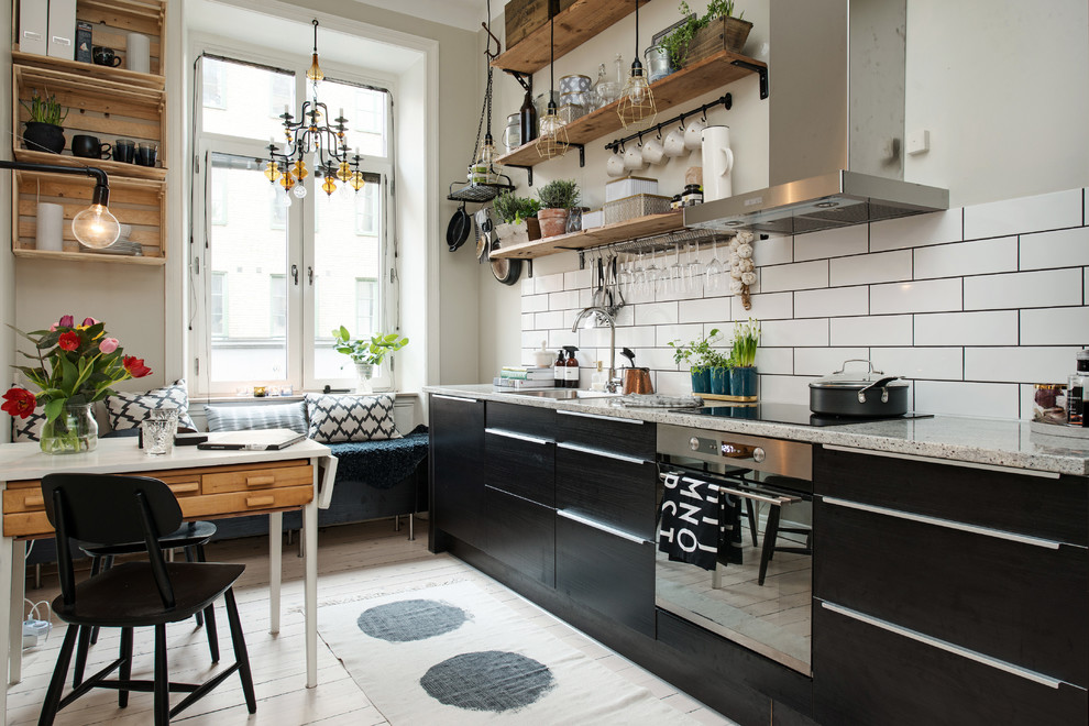 Exempel på ett nordiskt linjärt kök och matrum, med släta luckor, svarta skåp, granitbänkskiva, vitt stänkskydd, stänkskydd i tunnelbanekakel, rostfria vitvaror, en undermonterad diskho och målat trägolv