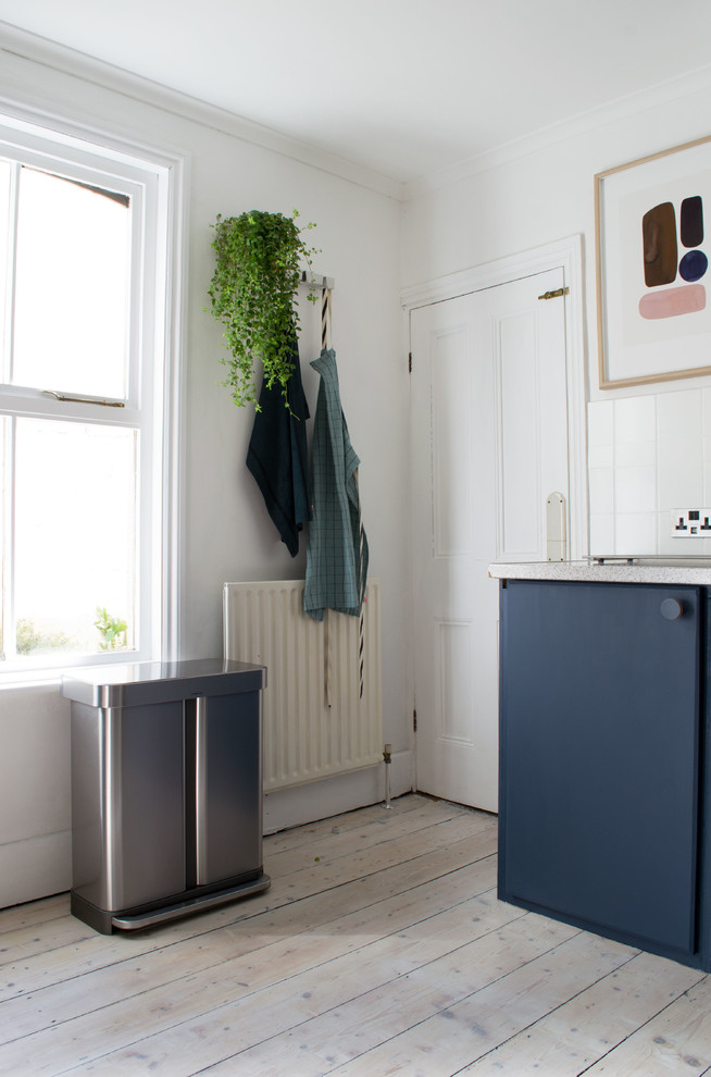Exempel på ett avskilt, mellanstort nordiskt flerfärgad flerfärgat kök, med en nedsänkt diskho, släta luckor, blå skåp, laminatbänkskiva, vitt stänkskydd, stänkskydd i cementkakel, rostfria vitvaror, ljust trägolv och vitt golv