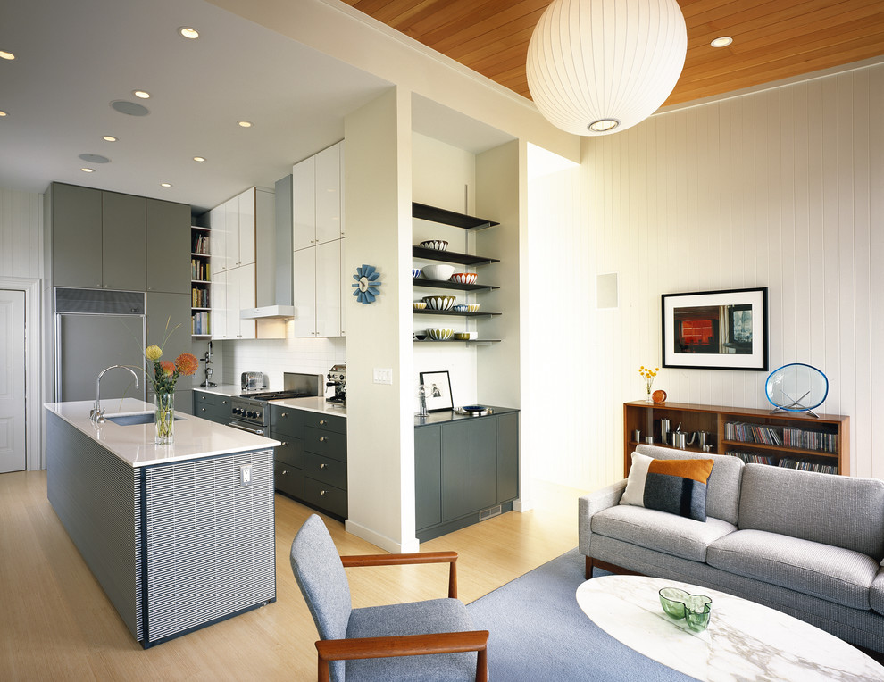 Cette image montre une cuisine ouverte encastrable design avec un évier encastré, un placard à porte plane, des portes de placard grises et une crédence blanche.