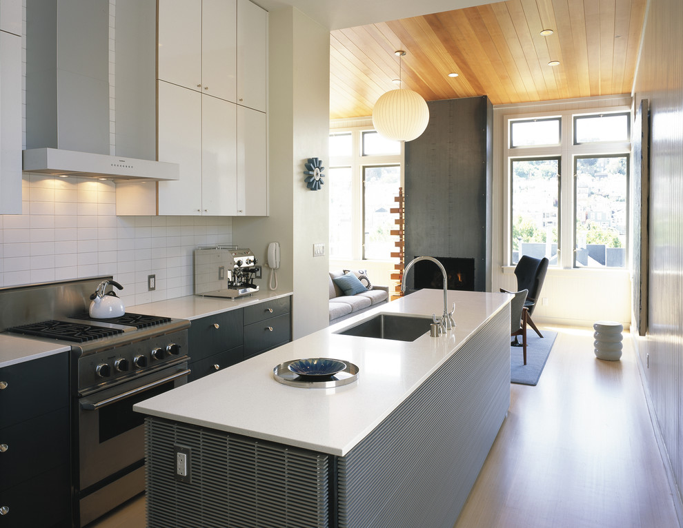 На фото: серо-белая кухня-гостиная в стиле модернизм с техникой из нержавеющей стали, врезной мойкой, плоскими фасадами, серыми фасадами и белым фартуком