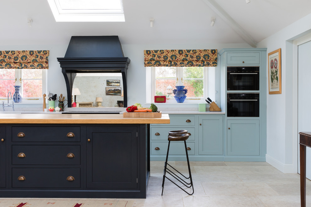На фото: кухня в классическом стиле с фасадами в стиле шейкер, синими фасадами, зеркальным фартуком, островом, серым полом, серой столешницей и окном с