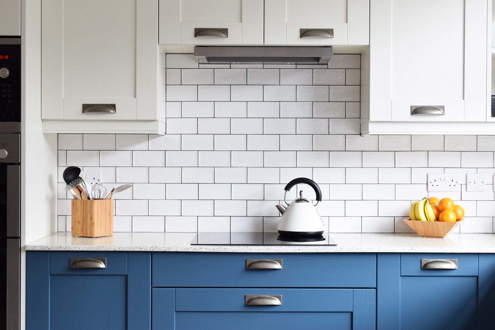 Modern inredning av ett mellanstort kök, med en rustik diskho, skåp i shakerstil, blå skåp, bänkskiva i återvunnet glas, vitt stänkskydd, stänkskydd i keramik, linoleumgolv, en halv köksö och grått golv