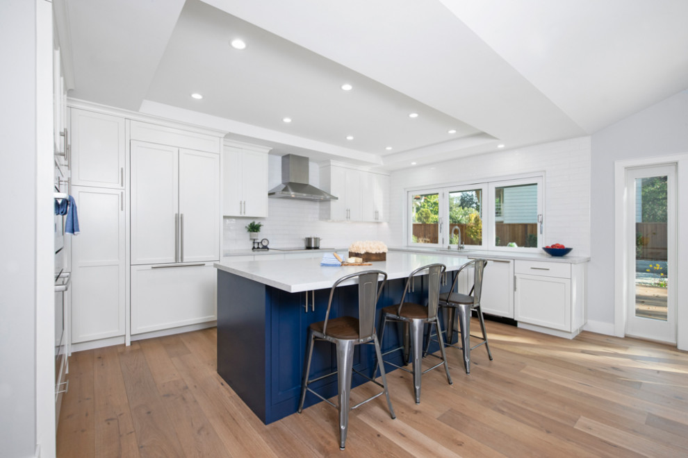 Inspiration for a medium sized classic u-shaped open plan kitchen in San Francisco with a submerged sink, shaker cabinets, white cabinets, engineered stone countertops, white splashback, ceramic splashback, stainless steel appliances, light hardwood flooring, an island, brown floors, white worktops and a coffered ceiling.