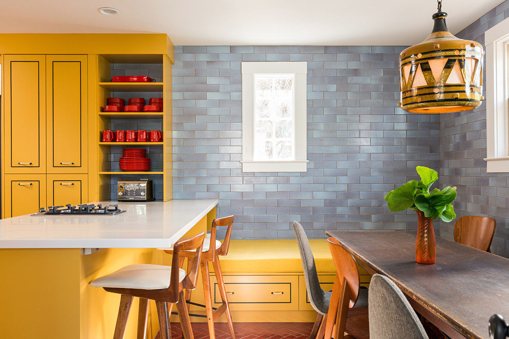 Trendy eat-in kitchen photo in Boston with yellow cabinets, an undermount sink, flat-panel cabinets, blue backsplash, stainless steel appliances and an island