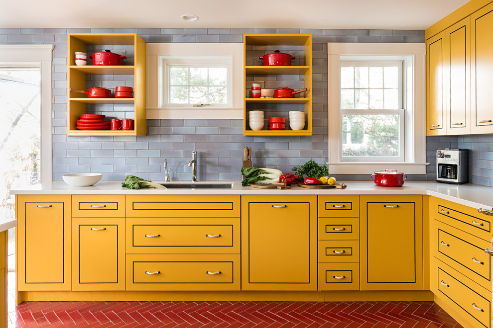 Photo of a contemporary l-shaped kitchen in Boston with a submerged sink, yellow cabinets, blue splashback, flat-panel cabinets, stainless steel appliances and an island.