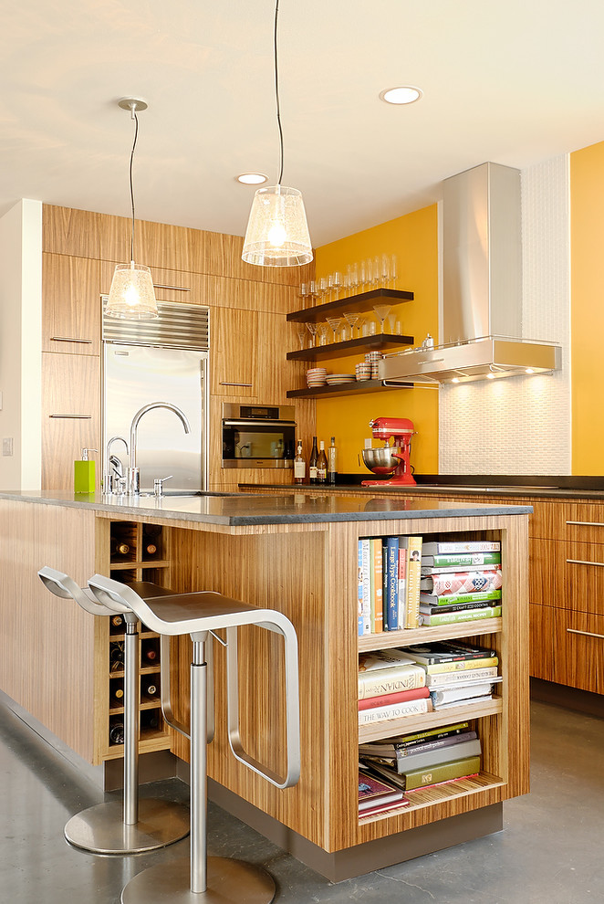 Modelo de cocina moderna con armarios con paneles lisos, puertas de armario de madera clara y electrodomésticos de acero inoxidable