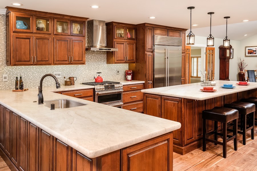 Example of a large classic l-shaped light wood floor and brown floor eat-in kitchen design in Sacramento with an undermount sink, raised-panel cabinets, dark wood cabinets, quartzite countertops, gray backsplash, mosaic tile backsplash, stainless steel appliances, an island and white countertops
