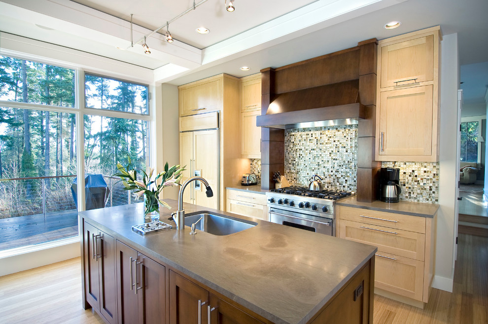 Inspiration for a transitional galley medium tone wood floor kitchen remodel in Seattle with an undermount sink, shaker cabinets, light wood cabinets, multicolored backsplash, mosaic tile backsplash, stainless steel appliances and an island