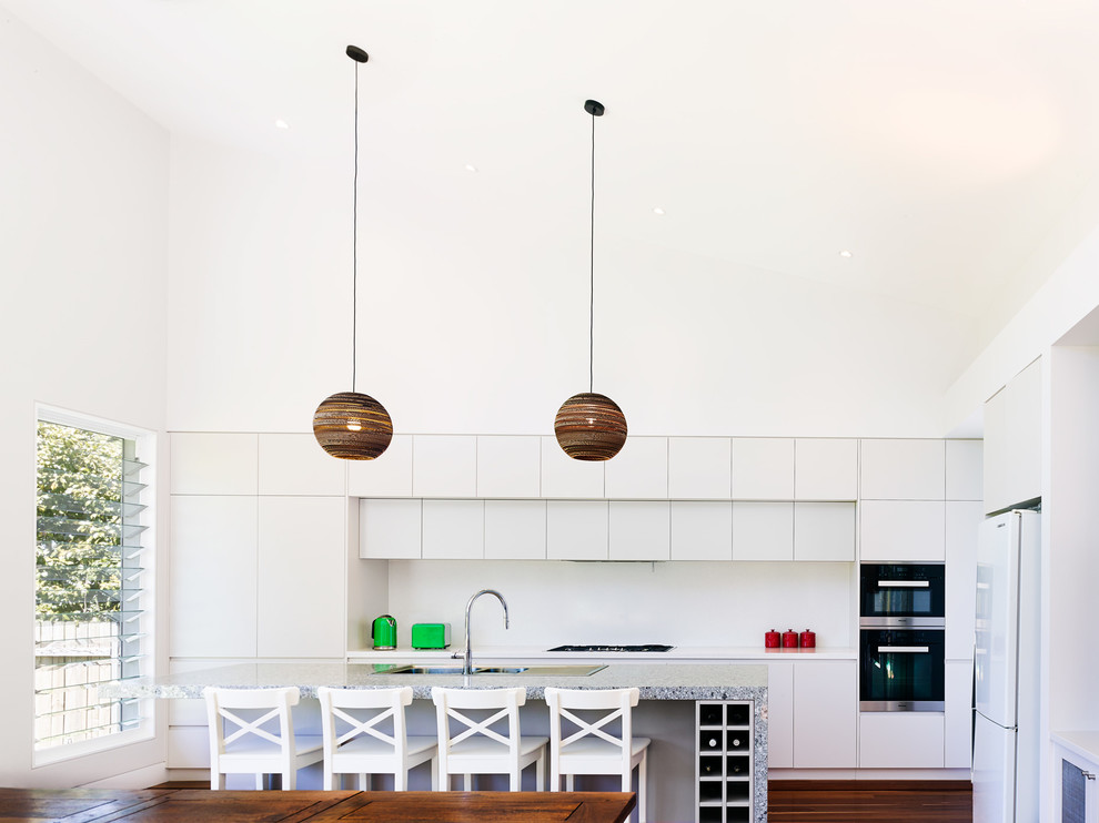 シドニーにあるコンテンポラリースタイルのおしゃれなキッチン (フラットパネル扉のキャビネット、白いキャビネット、シルバーの調理設備、無垢フローリング) の写真