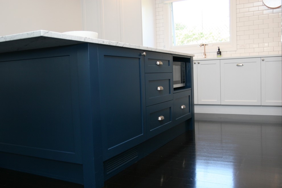 Exempel på ett mellanstort modernt kök, med en integrerad diskho, skåp i shakerstil, blå skåp, marmorbänkskiva, vitt stänkskydd, stänkskydd i keramik, rostfria vitvaror, mörkt trägolv, en köksö och brunt golv