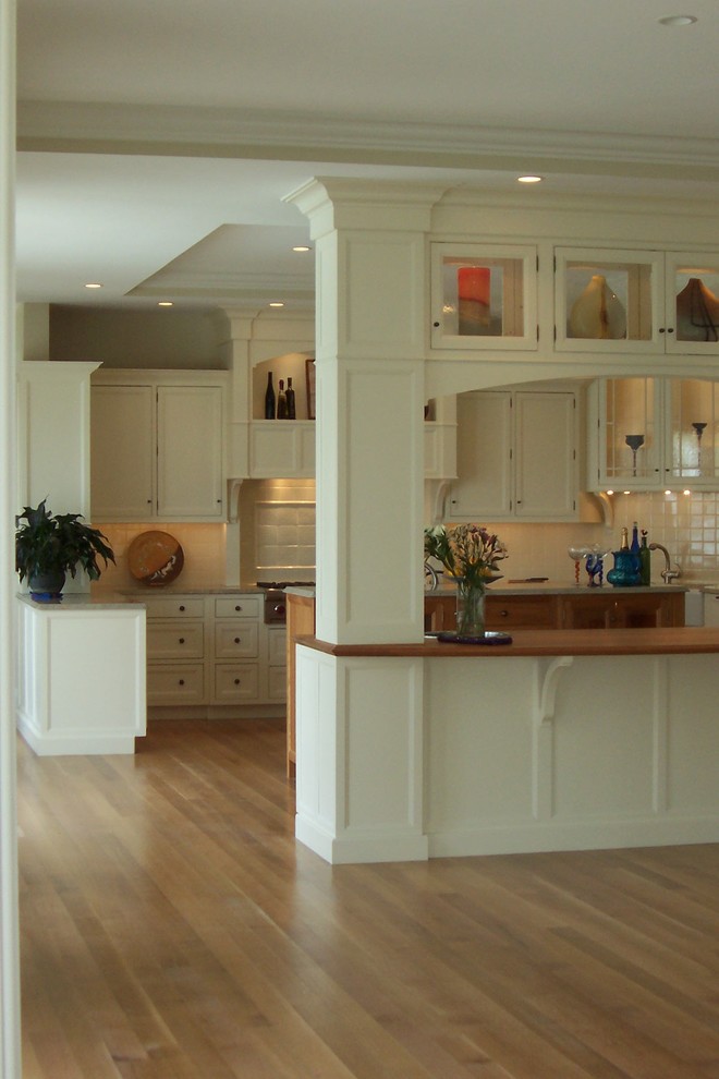 Example of a large classic u-shaped light wood floor open concept kitchen design in Other with an undermount sink, recessed-panel cabinets, white cabinets, granite countertops, white backsplash, porcelain backsplash, paneled appliances and an island