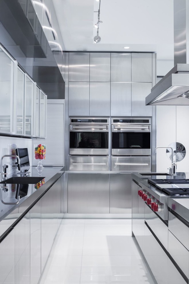 Photo of a contemporary kitchen/diner in Miami with flat-panel cabinets, stainless steel cabinets, stainless steel worktops, stainless steel appliances and an island.