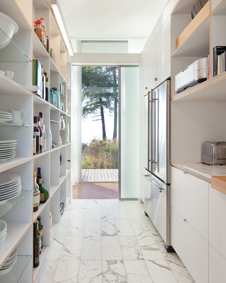 Идея дизайна: узкая параллельная, отдельная кухня в стиле модернизм с техникой из нержавеющей стали, мраморным полом, плоскими фасадами, белыми фасадами и деревянной столешницей без острова