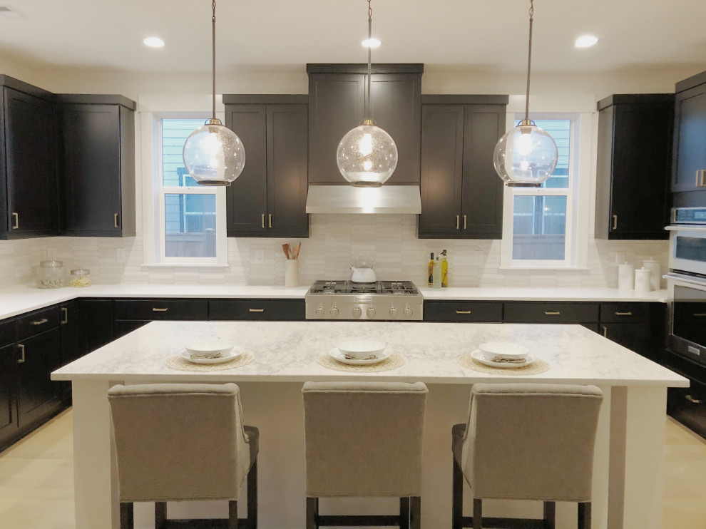 Design ideas for a traditional kitchen in Seattle with shaker cabinets, black cabinets, engineered stone countertops, white splashback, porcelain splashback, light hardwood flooring, an island and white worktops.