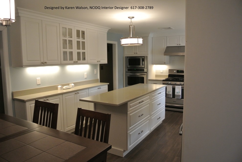 Example of a mid-sized classic l-shaped ceramic tile eat-in kitchen design in Boston with an undermount sink, raised-panel cabinets, white cabinets, quartz countertops, white backsplash, glass tile backsplash, stainless steel appliances and an island